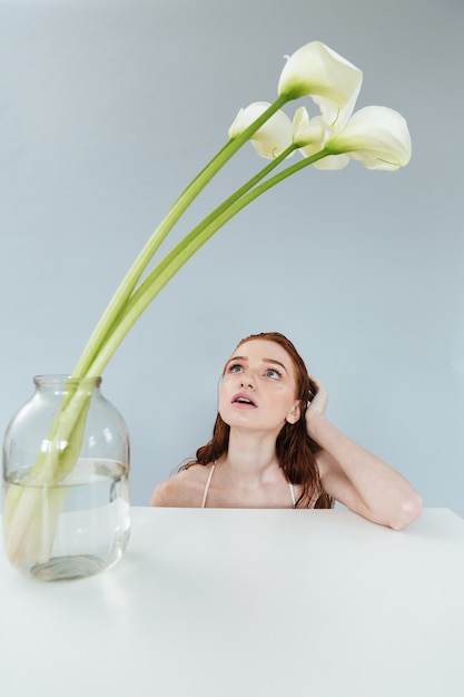 Free photo fashion portrait of a redheaded woman sitting at the table