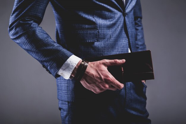 Fashion portrait of young businessman handsome model man dressed in elegant blue suit on gray