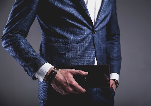 Fashion portrait of young businessman handsome model man dressed in elegant blue suit on gray