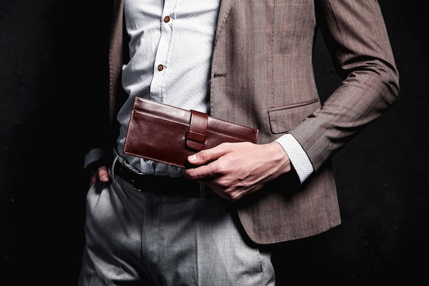 Fashion portrait of young businessman handsome model man dressed in elegant brown suit with accessories