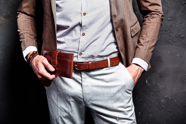 Fashion portrait of young businessman handsome model man dressed in elegant brown suit with accessories