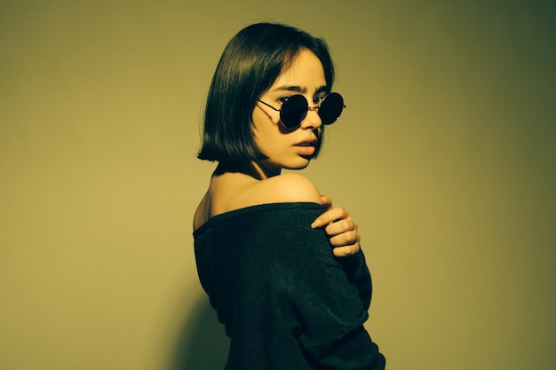 Free photo fashion portrait of young elegant woman in sunglasses. colored wall