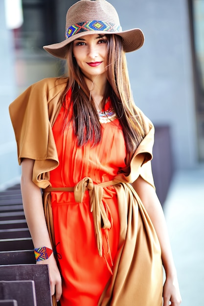 Fashion portrait of young hippie woman model in summer sunny day in bright colorful hipster clothes in hat