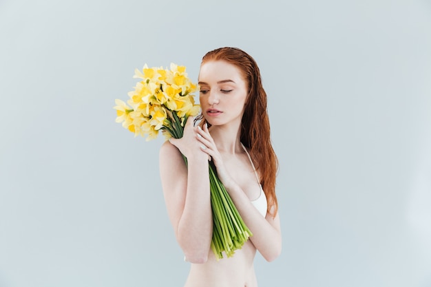 Fashion portrait of a young redheaded woman holding narcisuss flowers