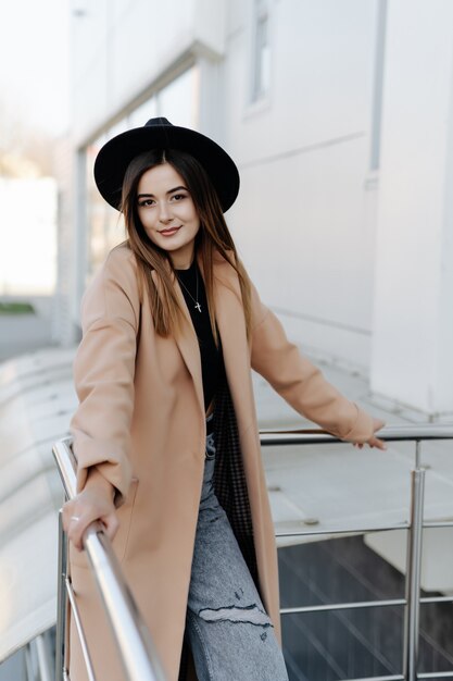 Fashion pretty woman wearing a black hat, sunglasses, coat outdoors