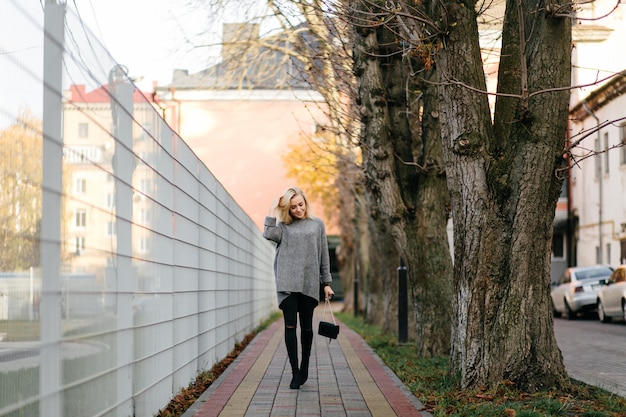 fashion street photo session of stylish young lady in a grey clothes