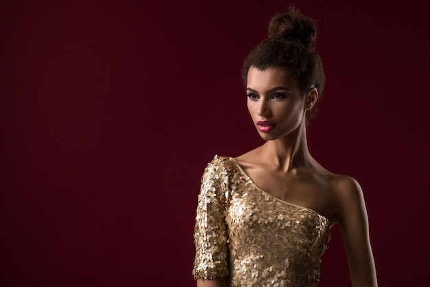 Free Photo fashion young african woman with make-up, in sexy gold dress. model on a claret background in the studio