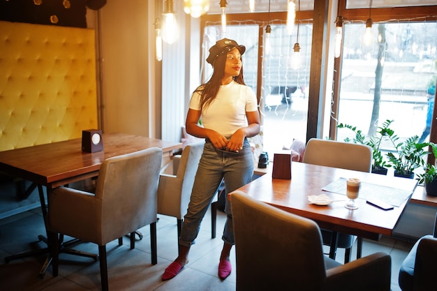 Fashionable african american woman in black cap chilling in cozy cafe