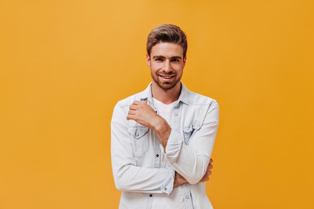 Free Photo fashionable bearded guy with stylish hairstyle in white modern jacket smiling and looking into camera on isolated backdrop