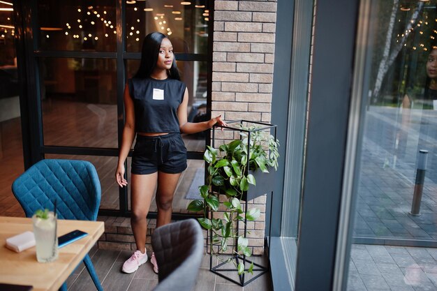 Fashionable feminist african american woman wear in black tshirt and shorts posed at restaurant