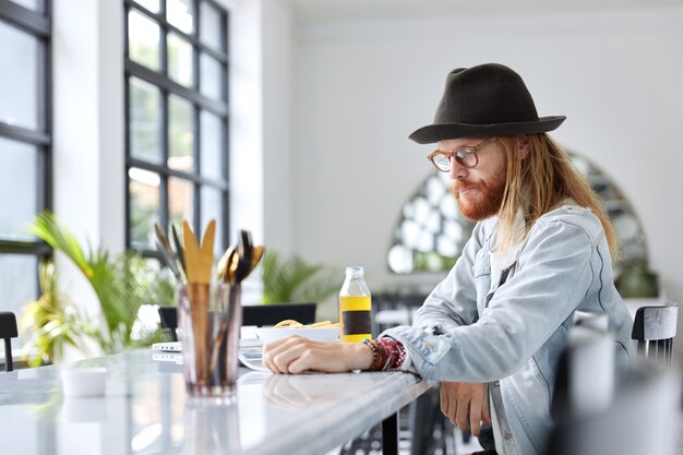 Fashionable hipster guy dressed in stylish black hat and denim shirt