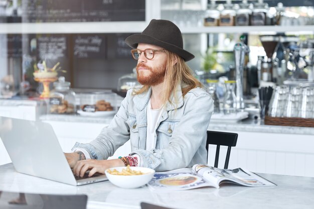 Fashionable hipster guy dressed in stylish black hat and denim shirt