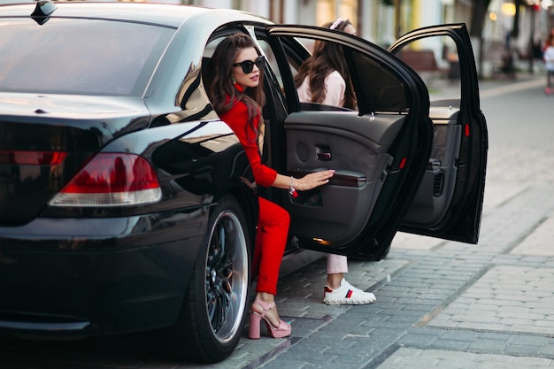 Free photo fashionable ladies going out of the car.