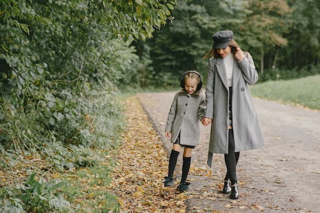 Fashionable mother with daughter. People walks outside. Woman in a gray coat.