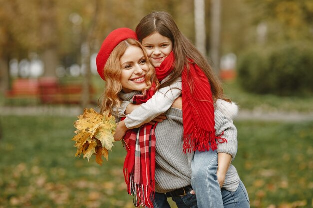 Fashionable mother with daughter. Yellow autumn. Woman in a red scarf.