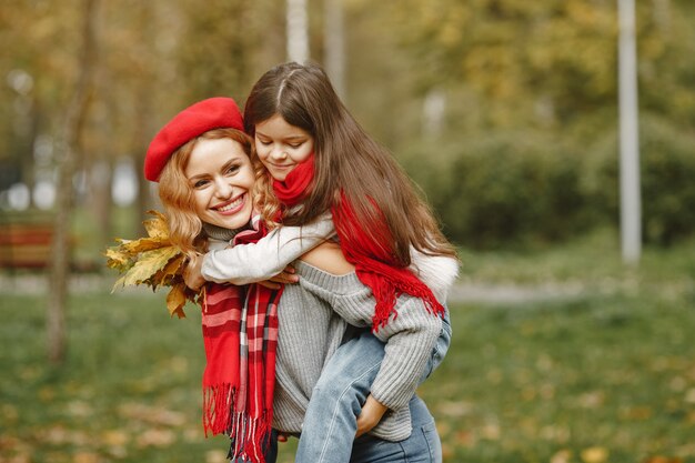 Fashionable mother with daughter. Yellow autumn. Woman in a red scarf.