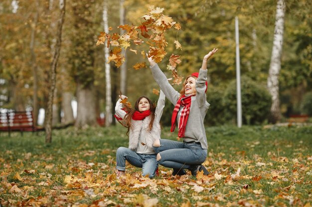 Fashionable mother with daughter. Yellow autumn. Woman in a red scarf.