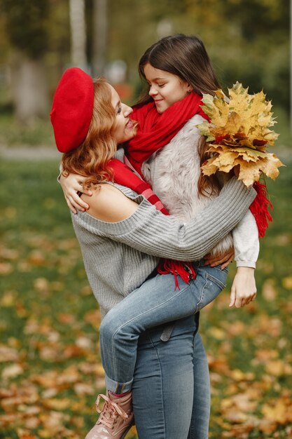 Fashionable mother with daughter. Yellow autumn. Woman in a red scarf.