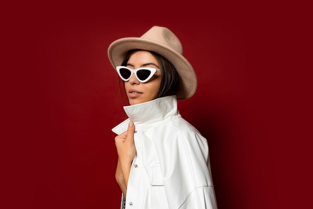 Fashionable woman in a hat, dress and white jacket , posing. Fashion awinter look.