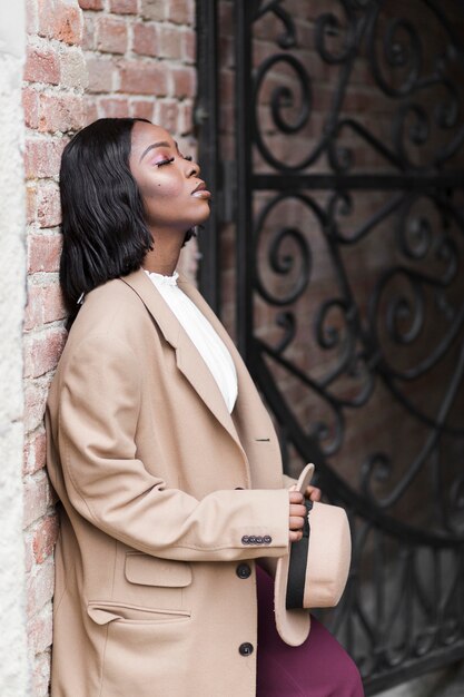 Fashionable woman posing while holding her hat down