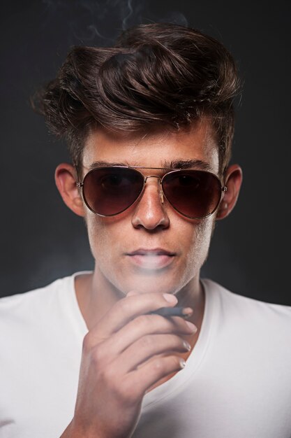 Fashionable young man exhaling cigarette smoke