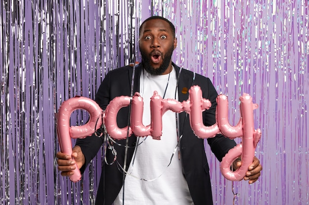 Free photo fashionable young man holding party balloons