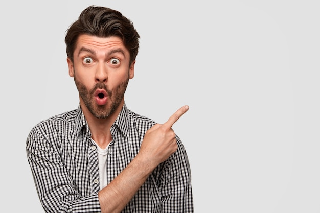 Fashionable young man with stubble, has surprised expression