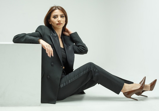 Fashionable young model sitting o the ground and looking at the camera High quality photo