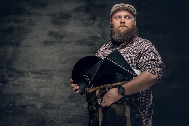 Fat bearded hipster man holds vinyl records.