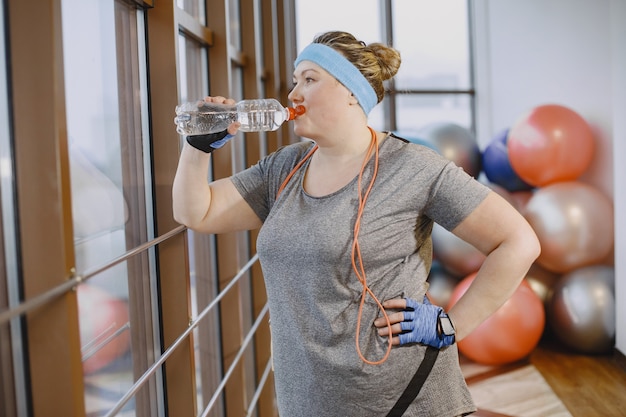 Fat woman dieting, fitness. Lady with rope. Woman in gray sportsuit.