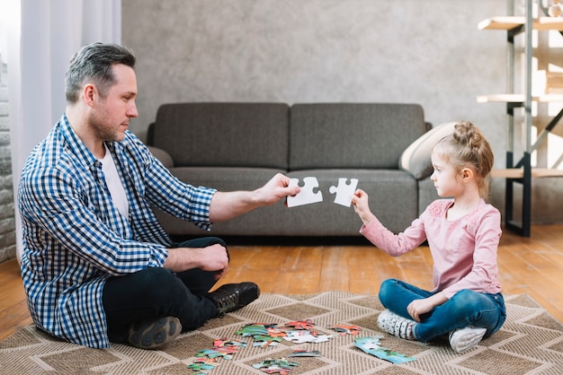 Father and daughter hand holding jigsaw puzzle piece