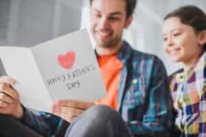 Free photo father and daughter looking at hand drawn card on fathers day