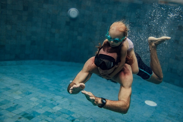 Father and daughter swimming together in pool