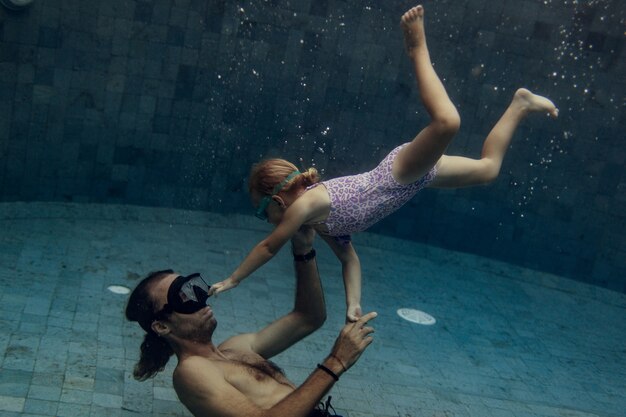 Father and daughter swimming together in pool