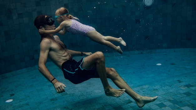 Father and daughter swimming together in pool