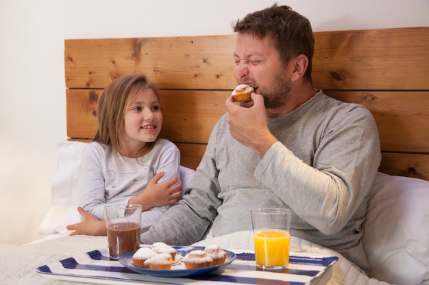 Free photo father eating a cupcake next to his daughter