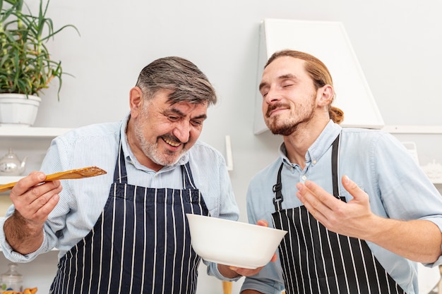 Father and funny son tasting a dish