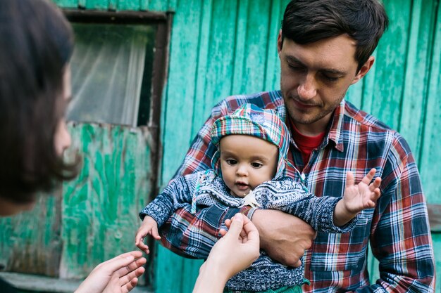 Father holding baby standing outside of house