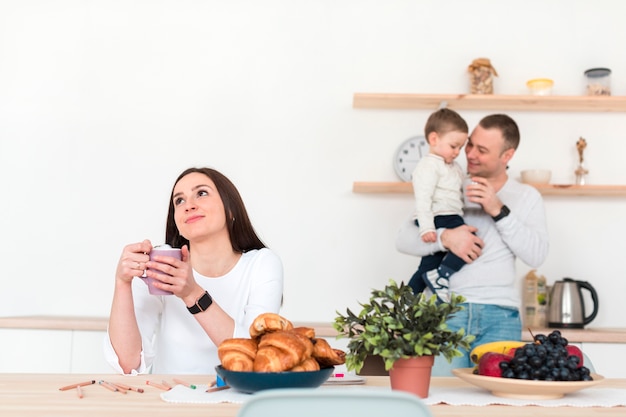 Father holding child while mother is at table in the kitchen