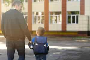 Free photo father and kid on first school day back view