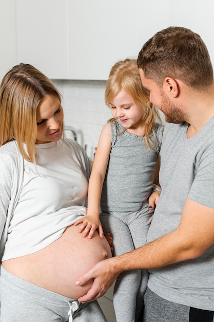 Father and little girl touching mother belly