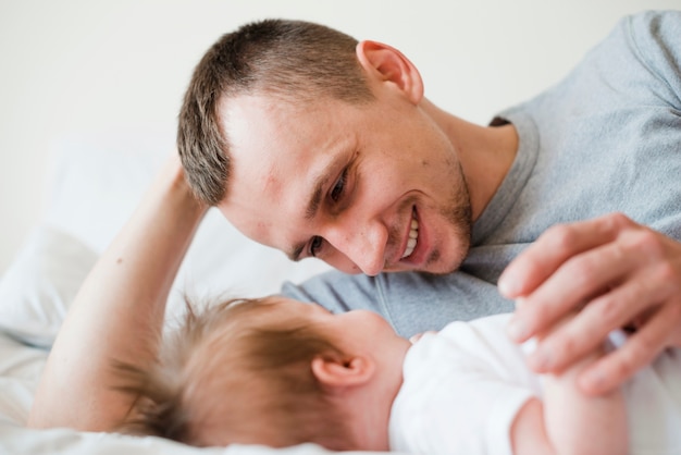 Father lying with baby in bed