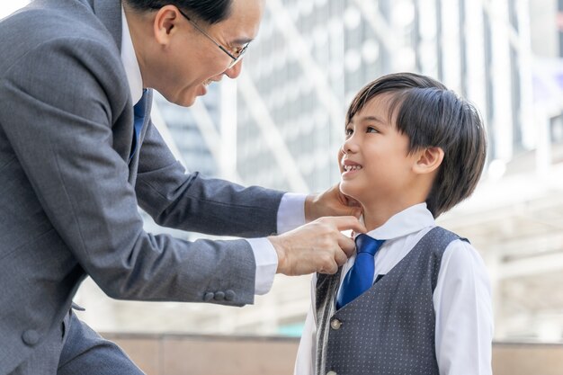 Father made the collar of the suit for his son on business district urban