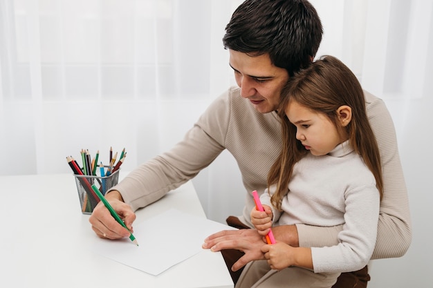 Free photo father playing with crayons with daughter