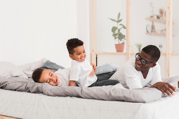 Father playing with his sons in bed