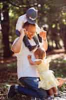 Free photo father plays with his son and daughter on green lawn in park