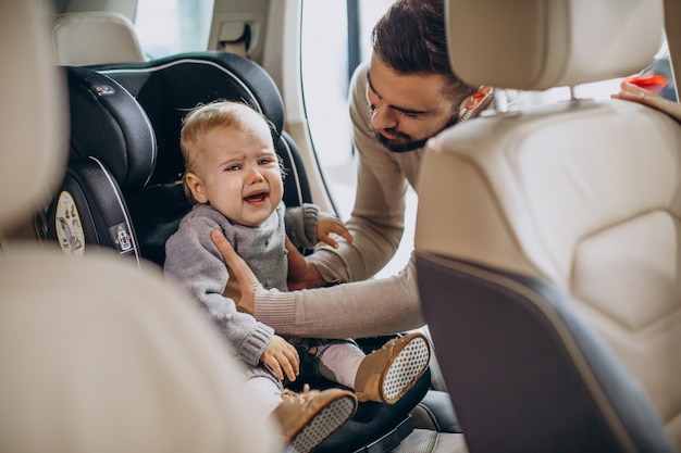 Father putting daughter in a car seat