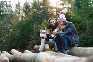 Free photo father and son drinking hot tea in the autumn forest