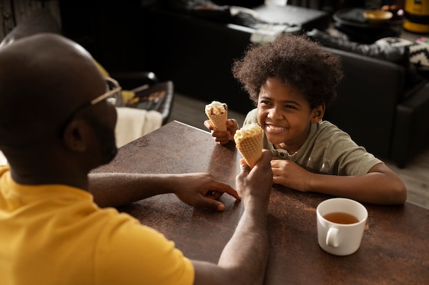 Father and son having ice cream together in the kitchen