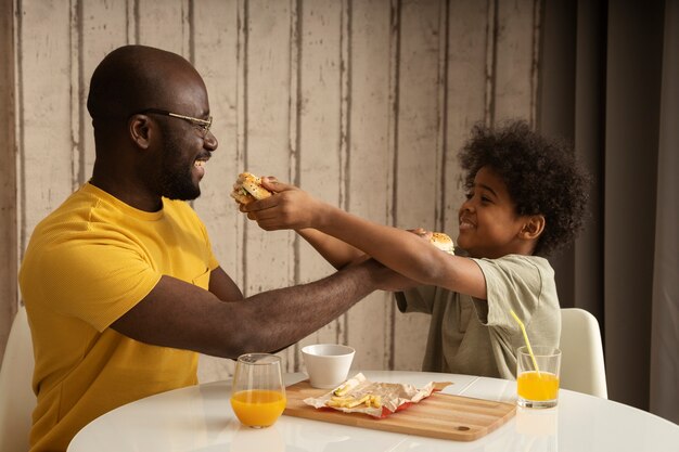 Father and son having lunch together and enjoying burgers and fries